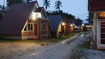 A row of small, single-story cottages with brick exteriors and pitched roofs, connected by a gravel path.