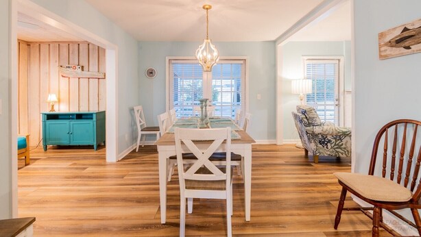 A dining area with a wooden table and chairs, a teal cabinet, and a chandelier. - 7 Dove Street - 3 Bedroom, newly remodeled home on North Forest Beach (Hilton Head Island)