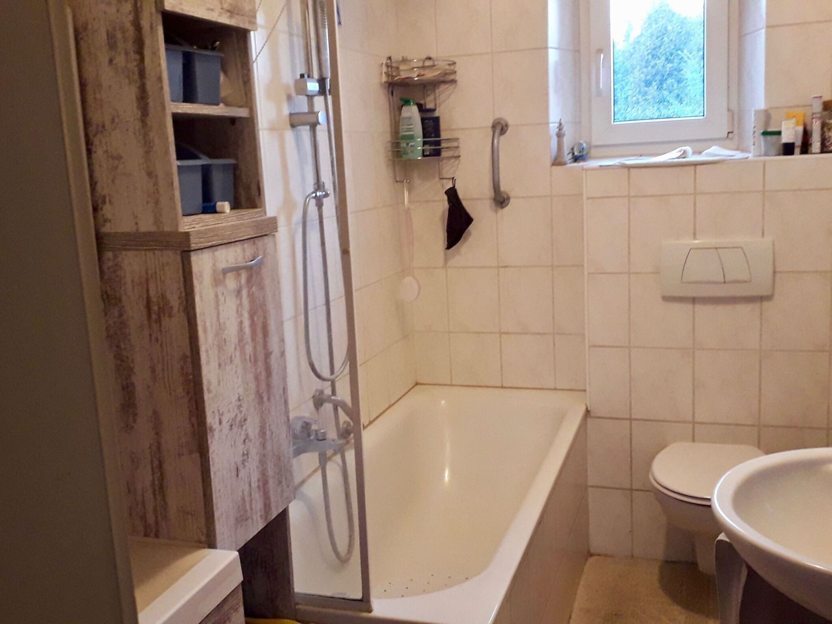 A bathroom with a bathtub, a toilet, and a window.