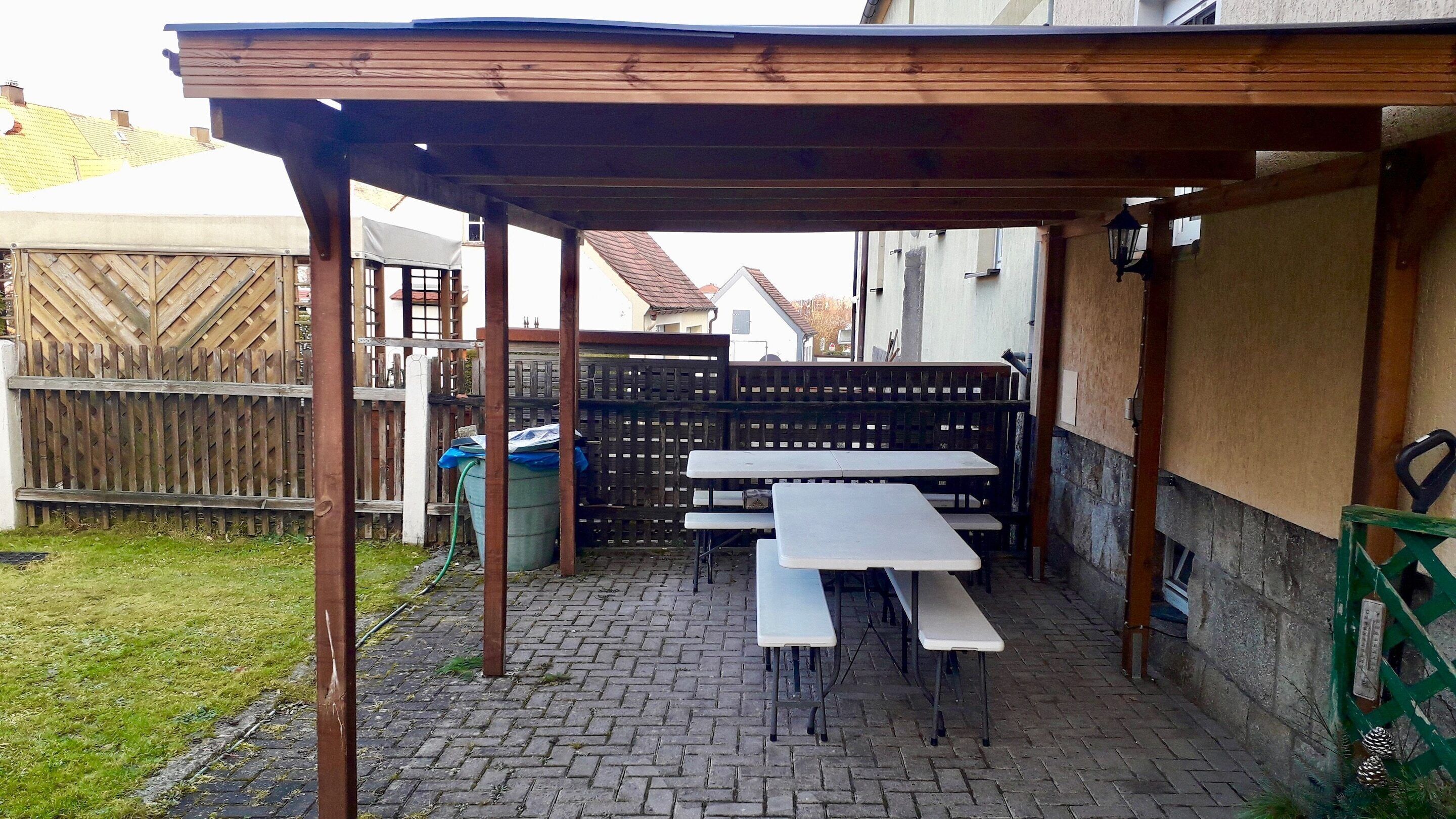 Una terrazza esterna con tavoli e una zona con posti a sedere coperta.