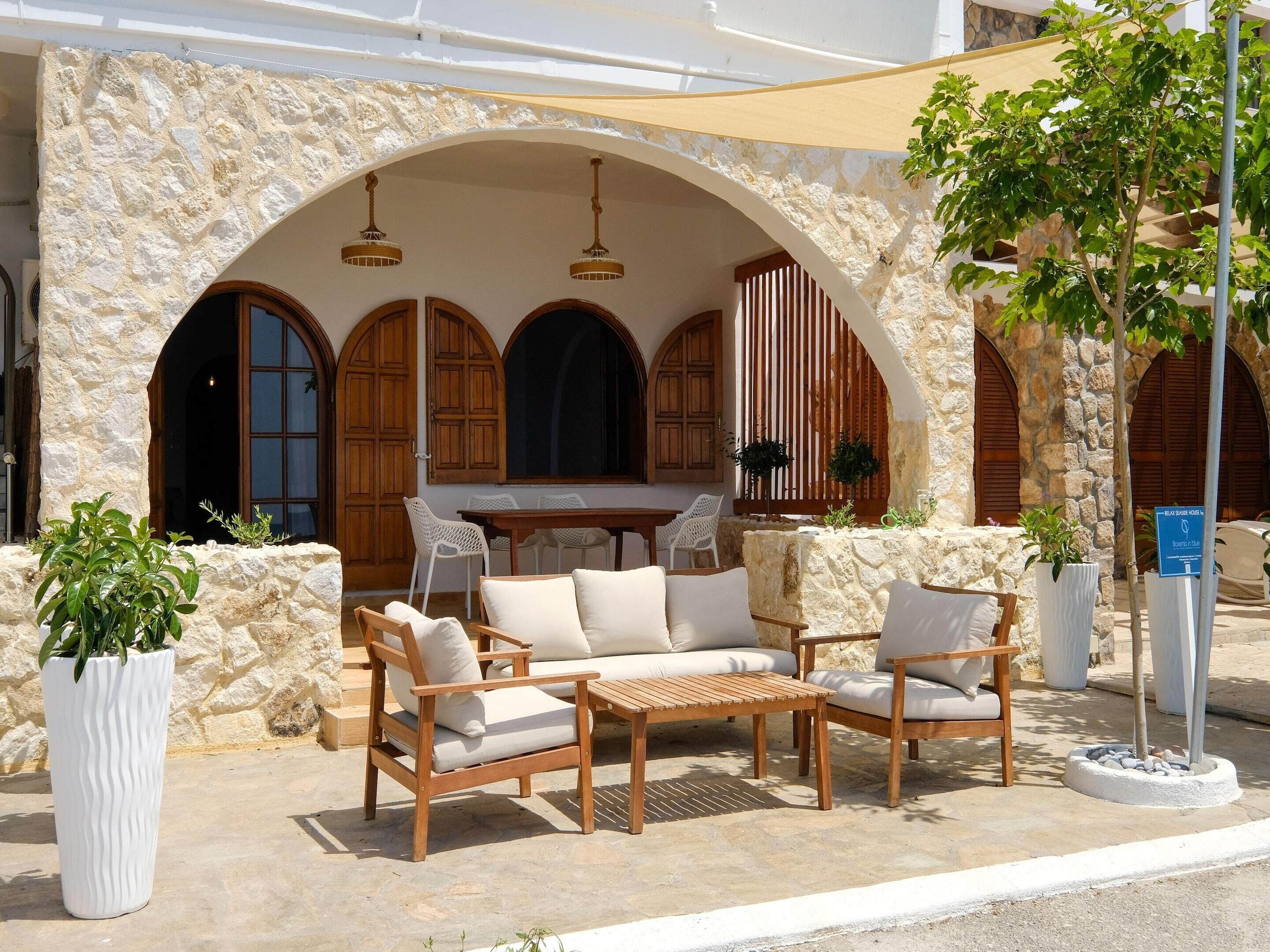 A stone-walled outdoor seating area with wooden furniture and potted plants.