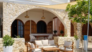 A stone-walled outdoor seating area with wooden furniture and potted plants.