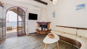 A living room with a stone floor, a fireplace, a sofa, and a television on the wall.