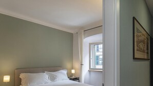 Een slaapkamer met een bed, nachtkastjes, een raam en een deur.