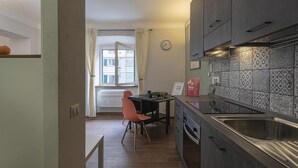 Een kleine keuken met een spoelbak, kastjes en een eethoek met een stoel en tafel.