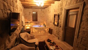 A stone-walled bathroom with a bathtub, a wooden ceiling, and a mirror. - Katapa Stone House (Nevsehir)