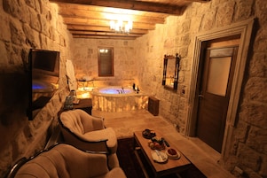 Un baño con paredes de piedra, una bañera y un espejo, con techo de madera.