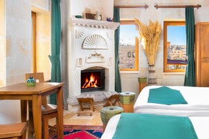 Habitación de hotel con chimenea, una cama, una mesa y vistas a la ciudad.