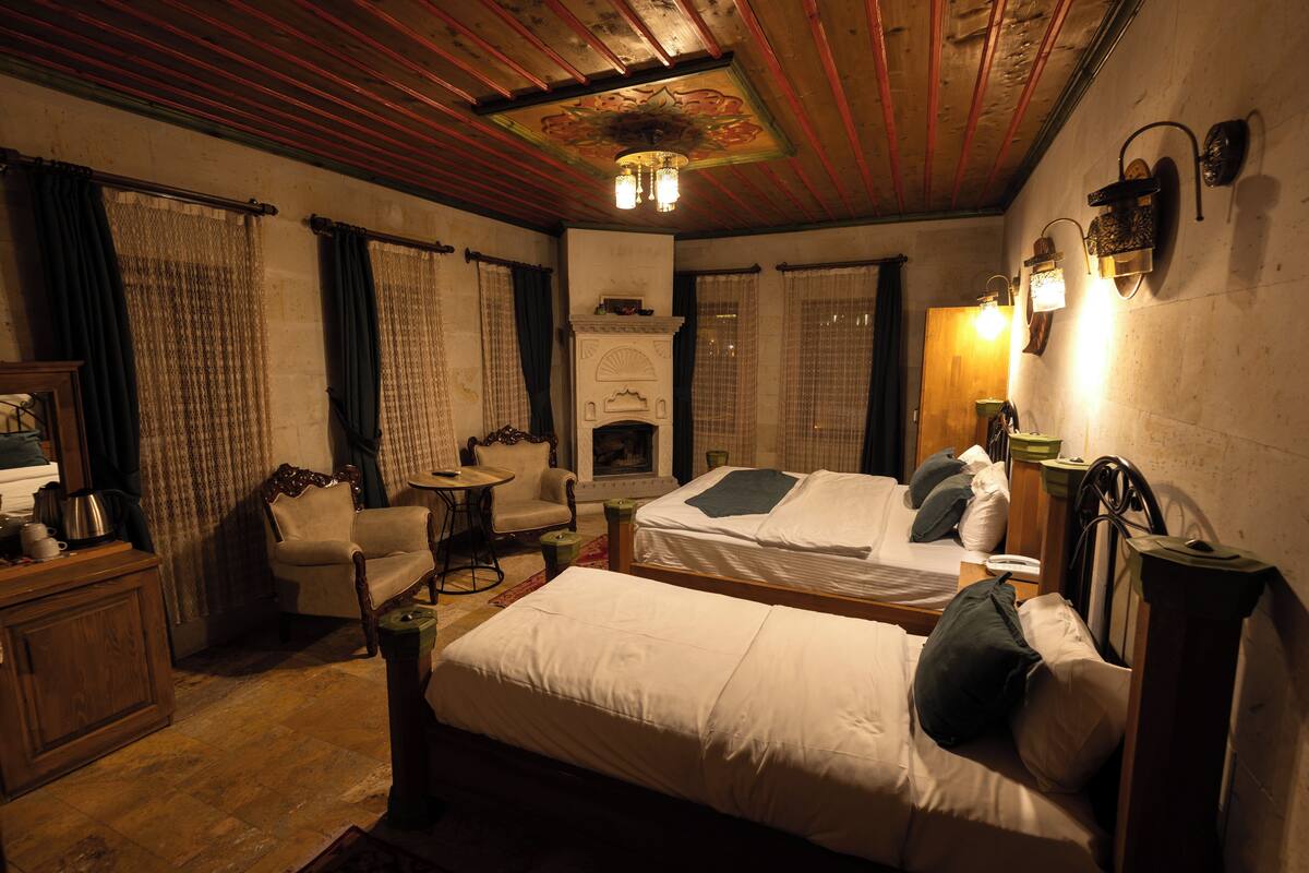 A traditional room with two beds, a fireplace, and a dining area.