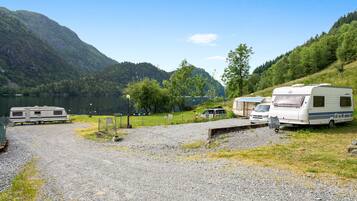 A campground with RVs and a picnic table near a lake, surrounded by hills.