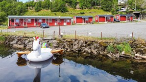 Un bâtiment rouge doté de plusieurs garages, une voiture garée et un cygne flottant sur une étendue d’eau.