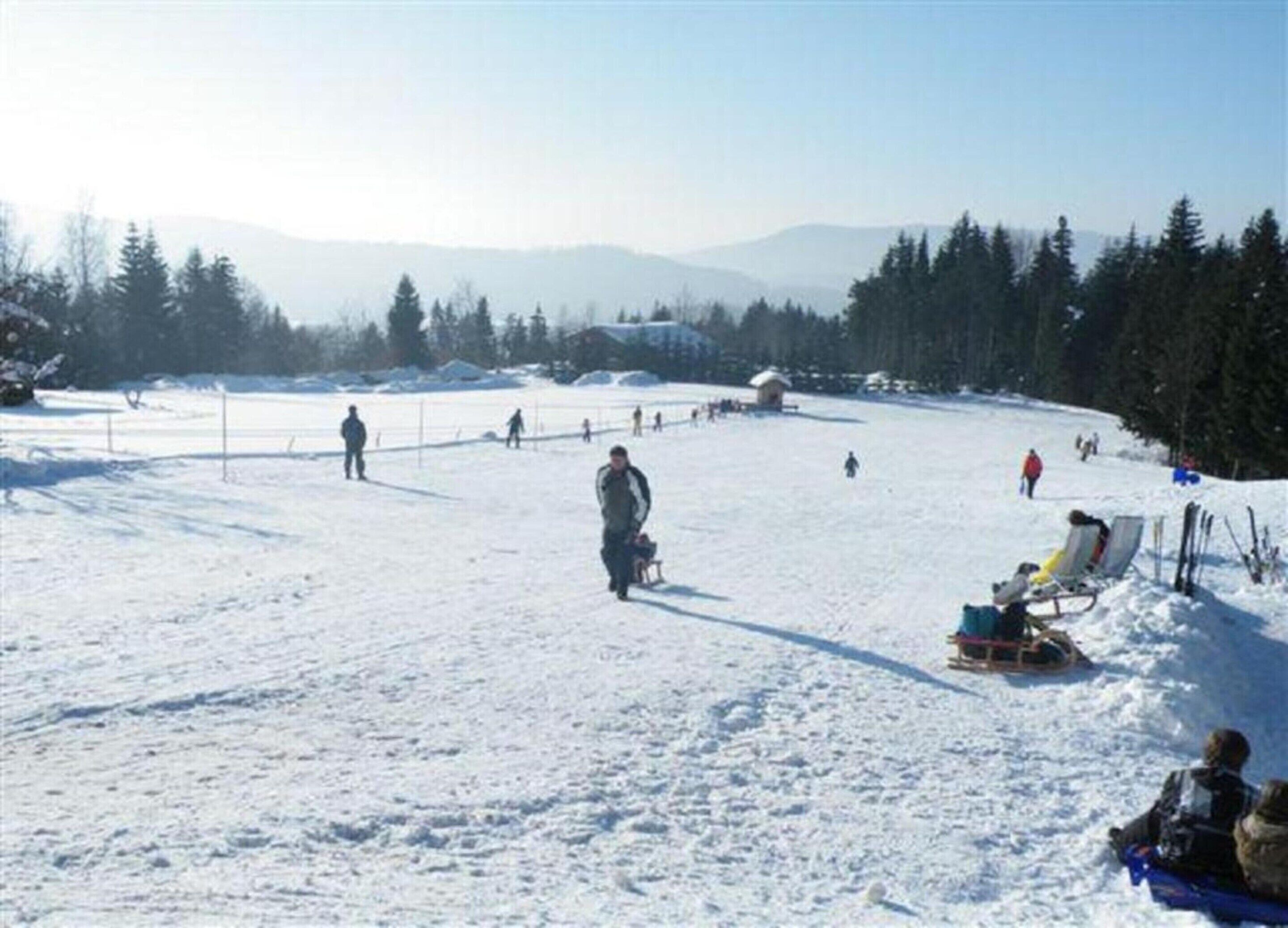 A snowy outdoor area with a sled and a few people.