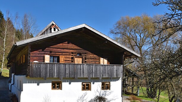 A traditional chalet with a wooden balcony, white exterior walls, and a sloped roof. - Hideaway With Hammock (Konzell)