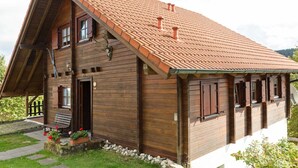 A wooden cabin with a sloped roof, a porch with a bench, and a stone pathway leading to the entrance. - Holzferienhaus in Hinterrod mit Sauna (Eisfeld)
