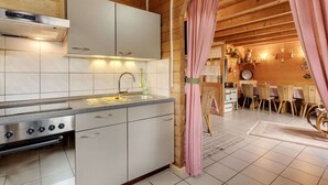A modern kitchen with white cabinets, stainless steel appliances, and a wooden ceiling. - Holzferienhaus in Hinterrod mit Sauna (Eisfeld)