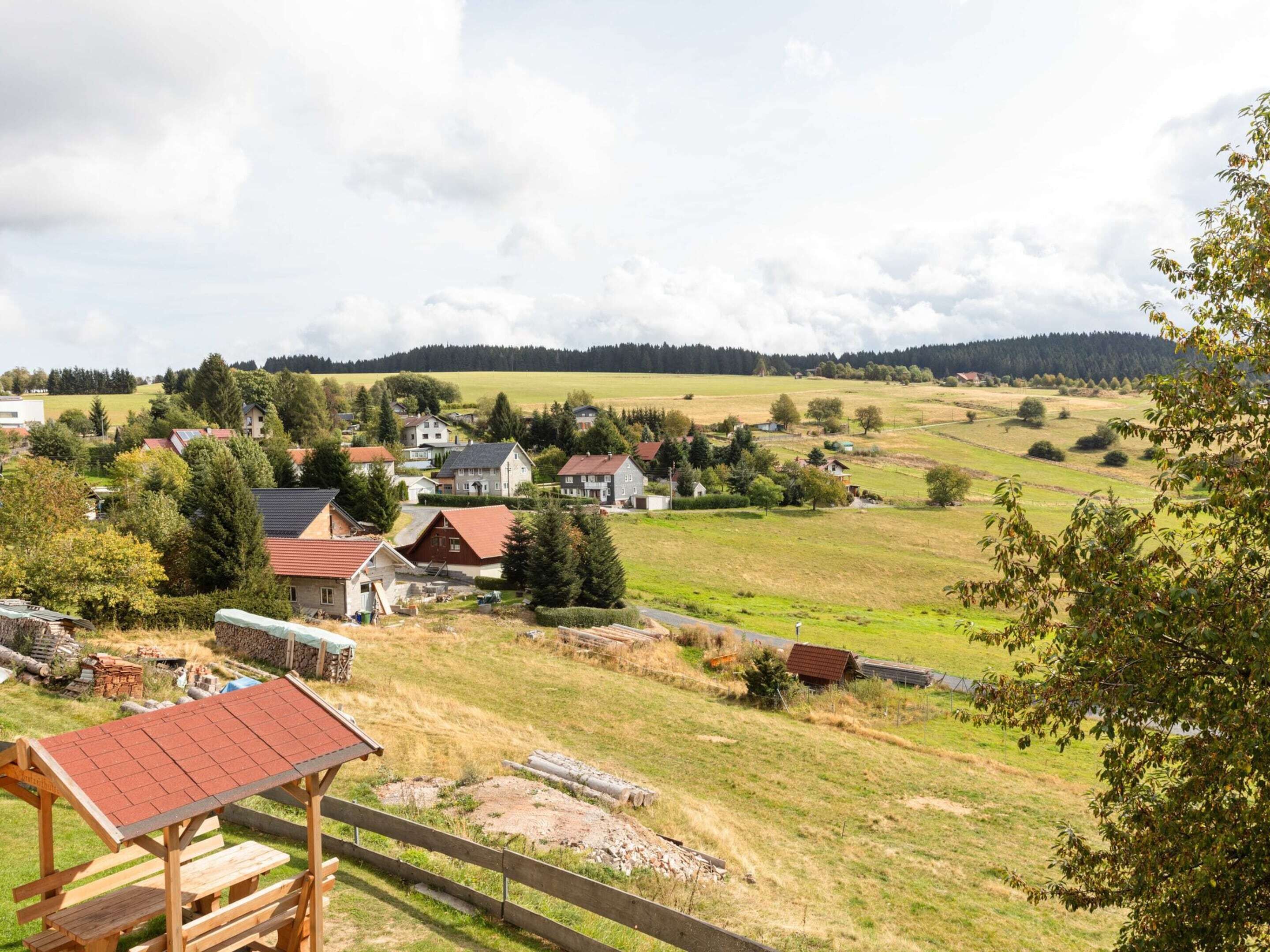 A rural village with houses, a wooden picnic table, and a fenced area.
