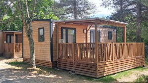 A row of wooden cabins with balconies, surrounded by trees.