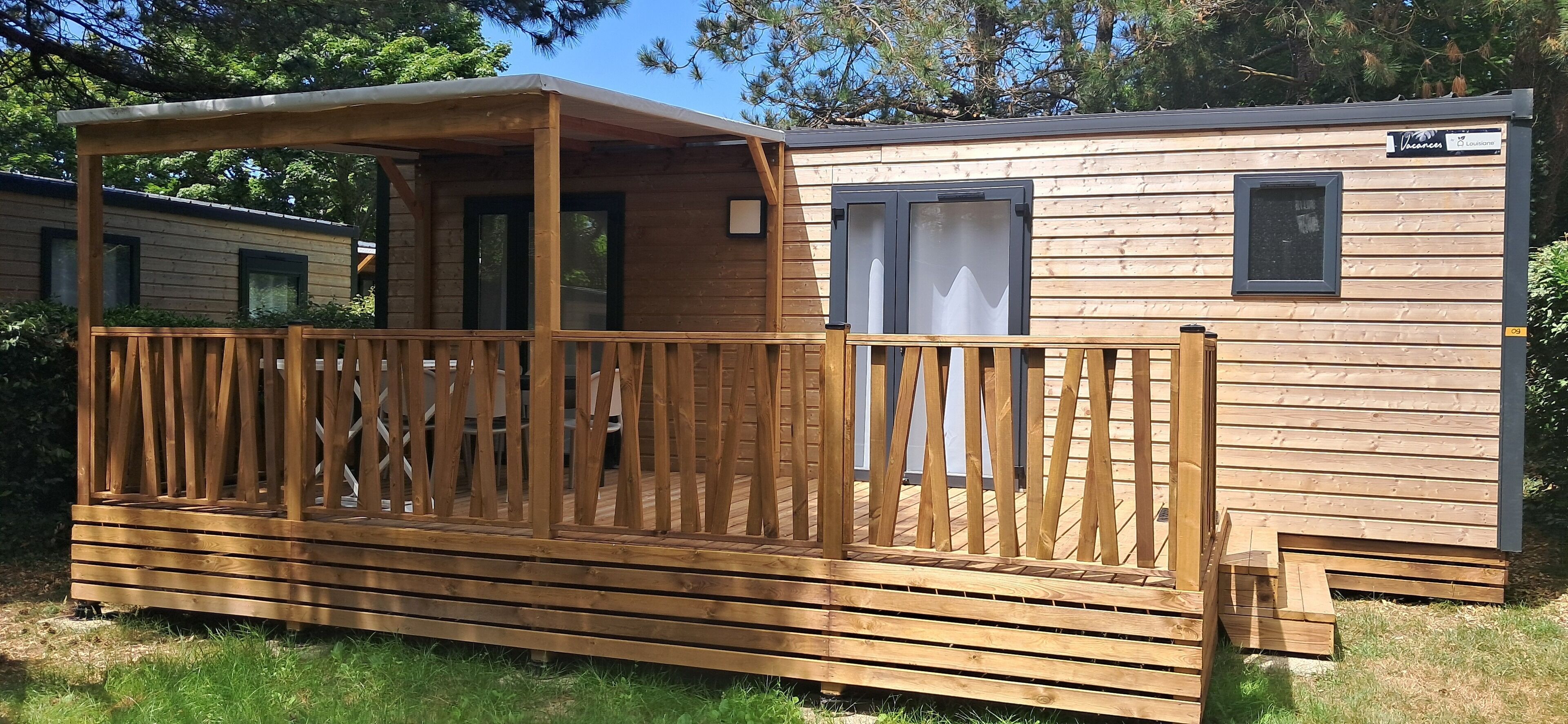 Une maison mobile en bois dotée d’un porche et d’une terrasse couverte.