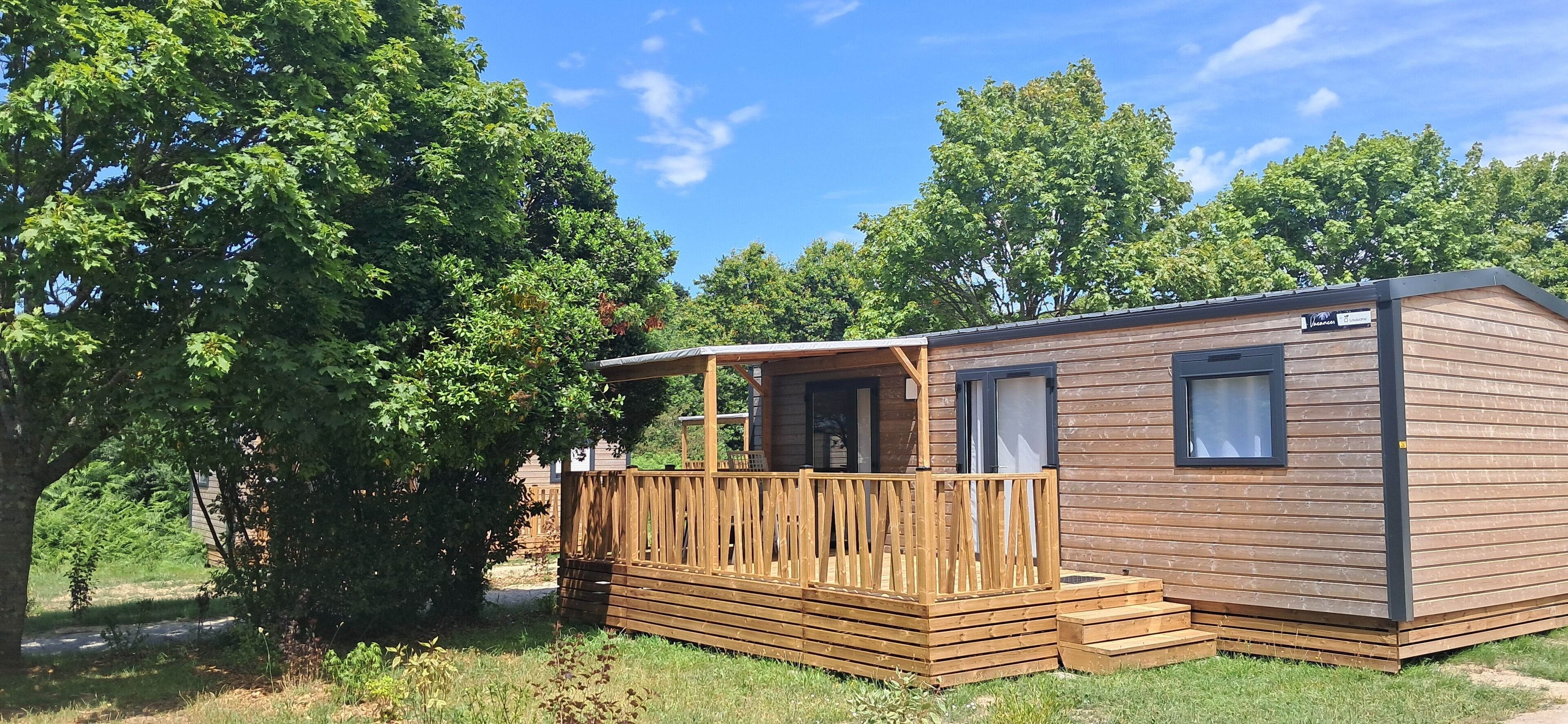 Une petite cabane en bois dotée d’une terrasse, entourée d’arbres.
