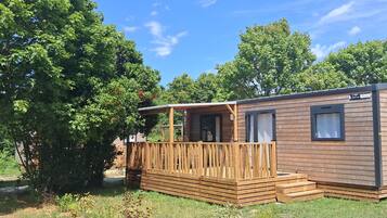 Une petite cabane en bois dotée d’une terrasse, entourée d’arbres.
