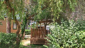A wooden cabin with a wooden deck and a pergola covered in vines.