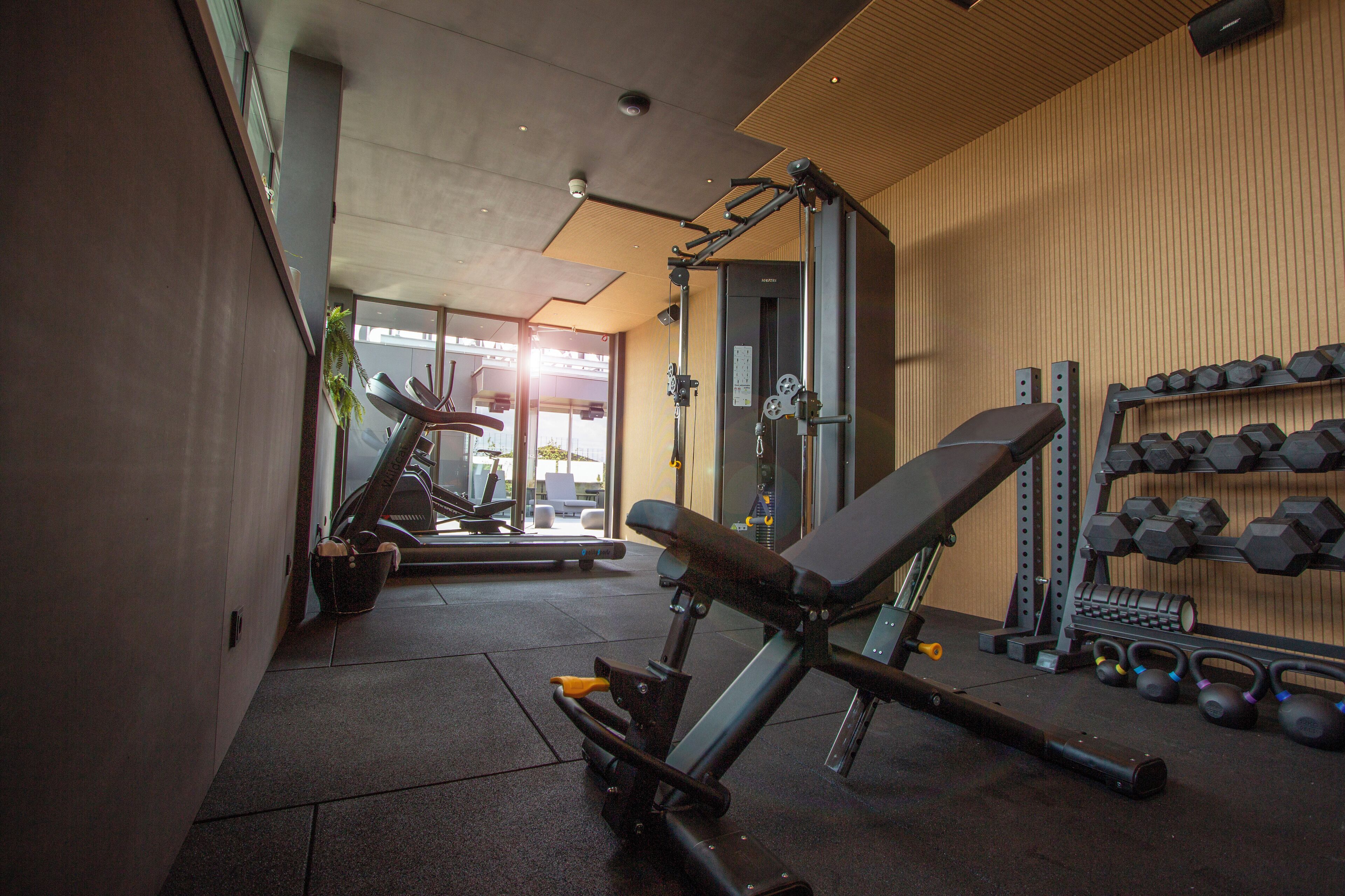 A gym with exercise equipment, including a bench and dumbbells.