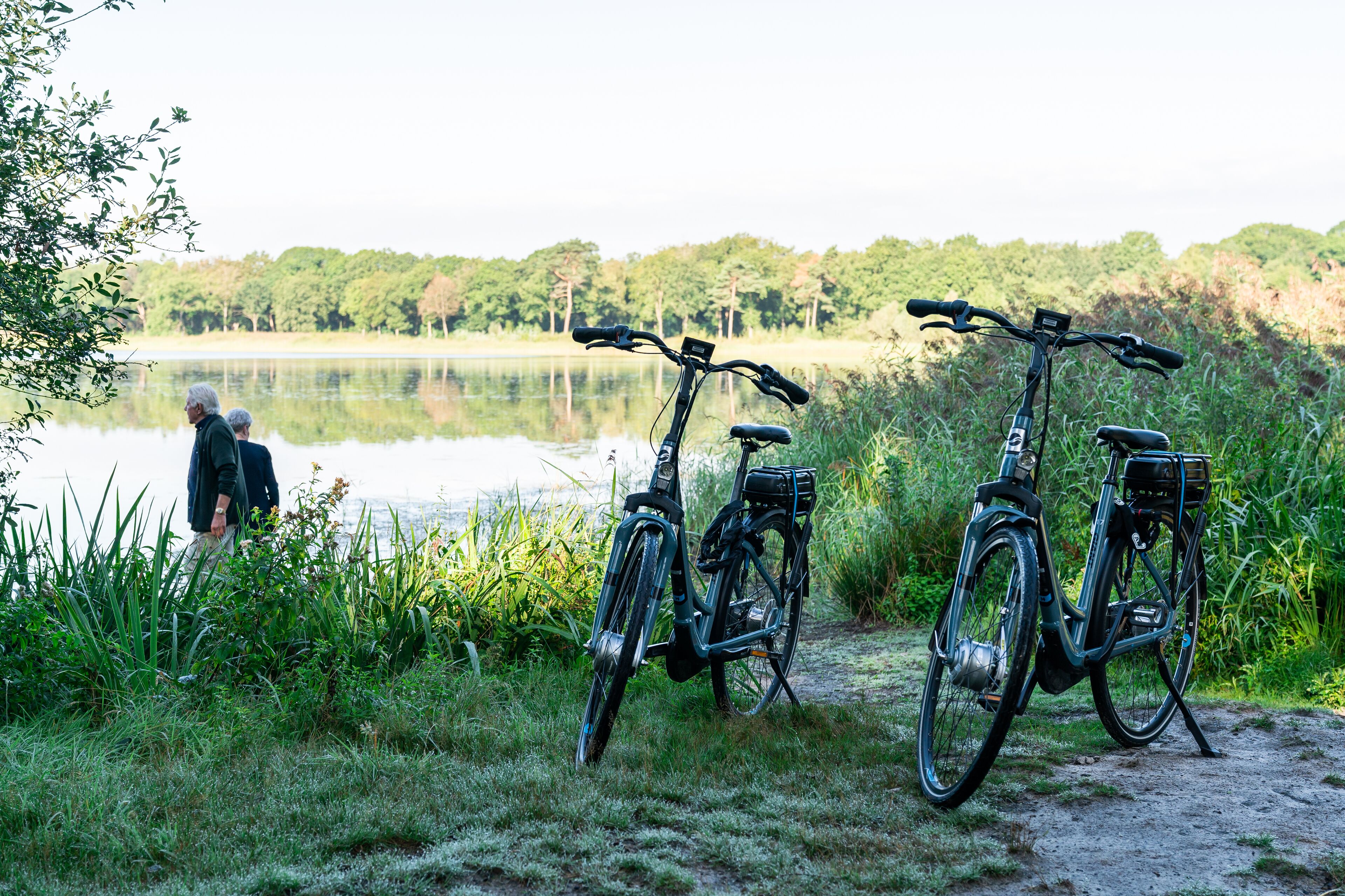 Un vélo est garé au bord d’un lac, et on aperçoit une personne au loin.