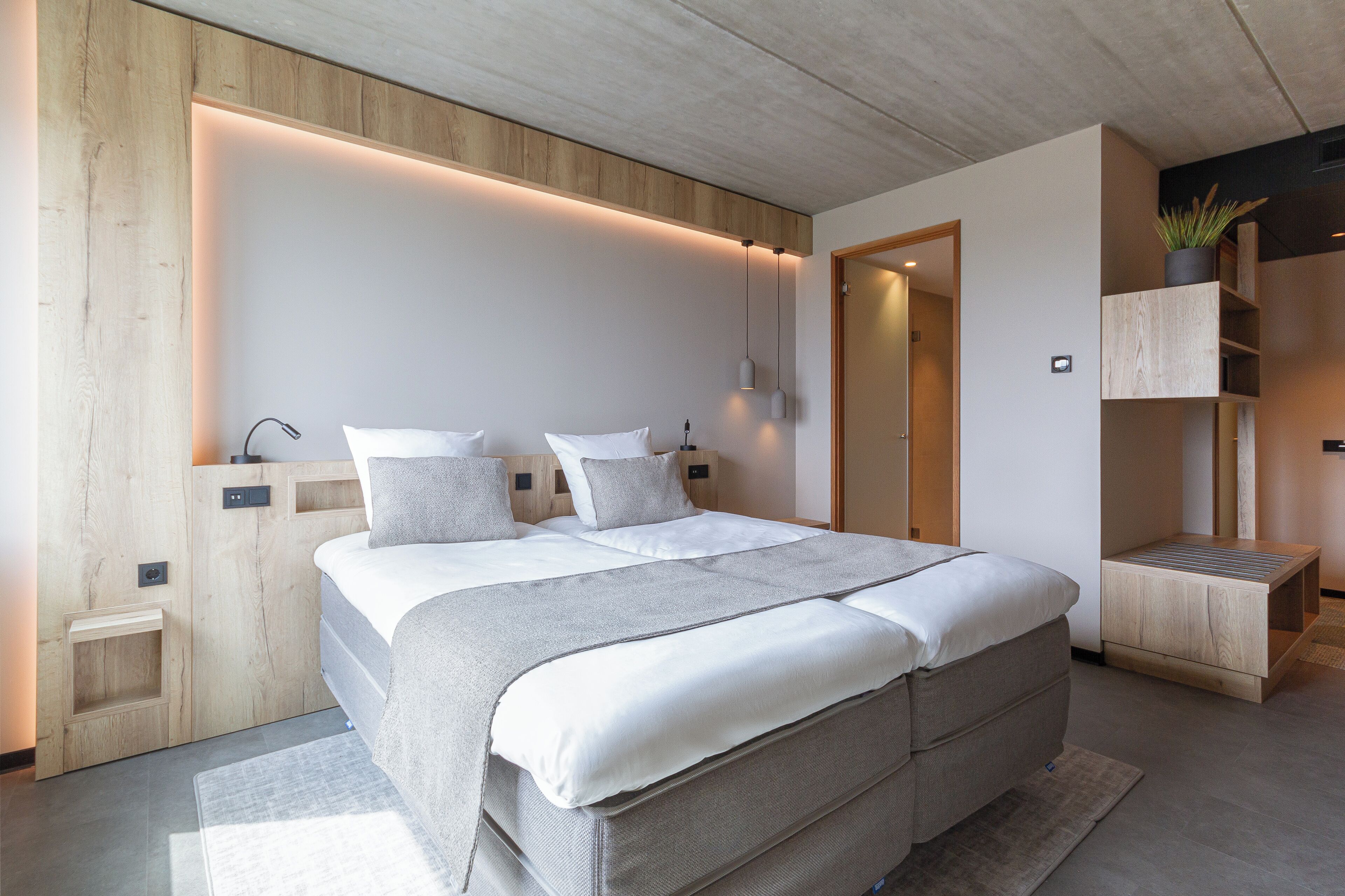 Une chambre moderne avec un grand lit, un lambris en bois et des rangements intégrés.