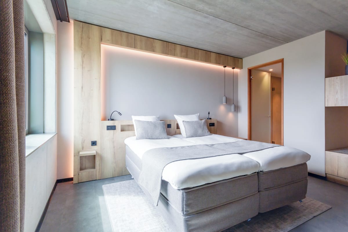 A modern bedroom with a large bed, bedside tables, and a built-in bench.