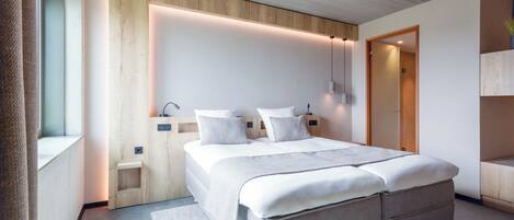 A modern bedroom with a large bed, bedside tables, and a built-in bench.