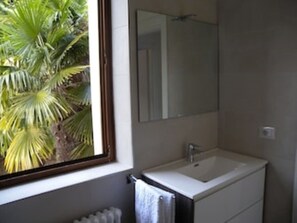 Un baño con ventana, lavamanos y espejo.