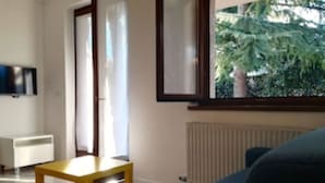 Un salon moderne avec un canapé bleu, une table basse en bois et une fenêtre donnant sur des arbres.