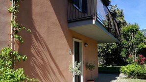 Un bâtiment à l’extérieur brun, avec une porte et deux plantes en pot placées au sol.