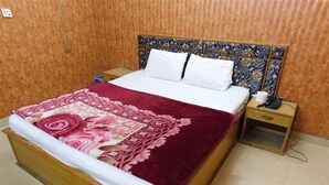 A bed with a floral bedspread, a wooden headboard, and a nightstand with a phone. - Hotel Al Noor (Lahore)
