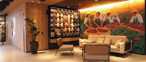 Un interior moderno con techo de madera, zona de estar con sofá y sillas, estantería y un mural de personas con sombreros.