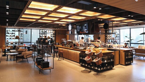 A modern coffee shop with a bar area, seating, and a display of coffee products. - AI HOTEL JAKARTA THAMRIN (Jakarta)