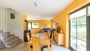 Una cocina moderna con comedor, estufa integrada y un amplio ventanal con vista a zonas verdes.