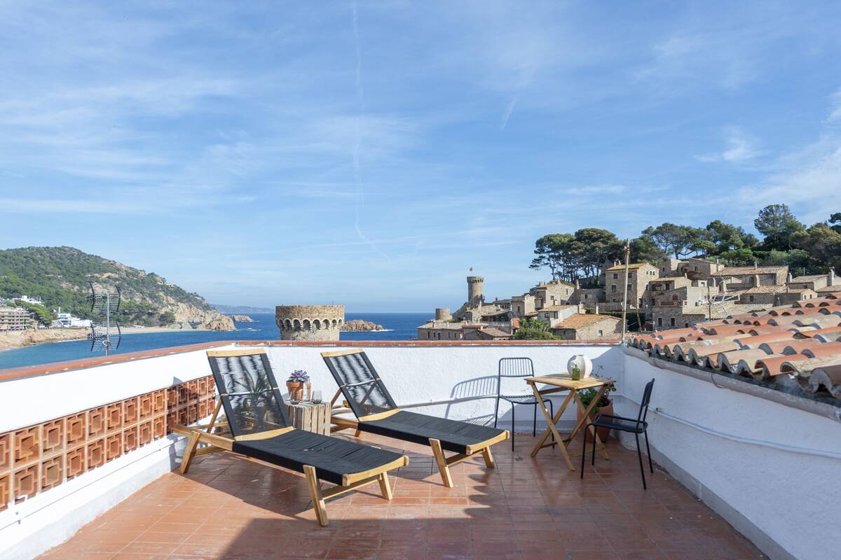 A terrace with two lounge chairs, a small table, and a potted plant.