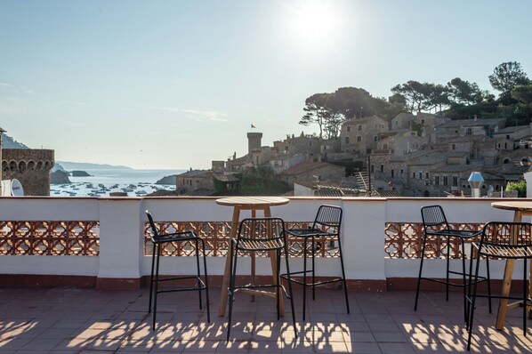 Une terrasse avec des places assises extérieures donnant sur une ville côtière.