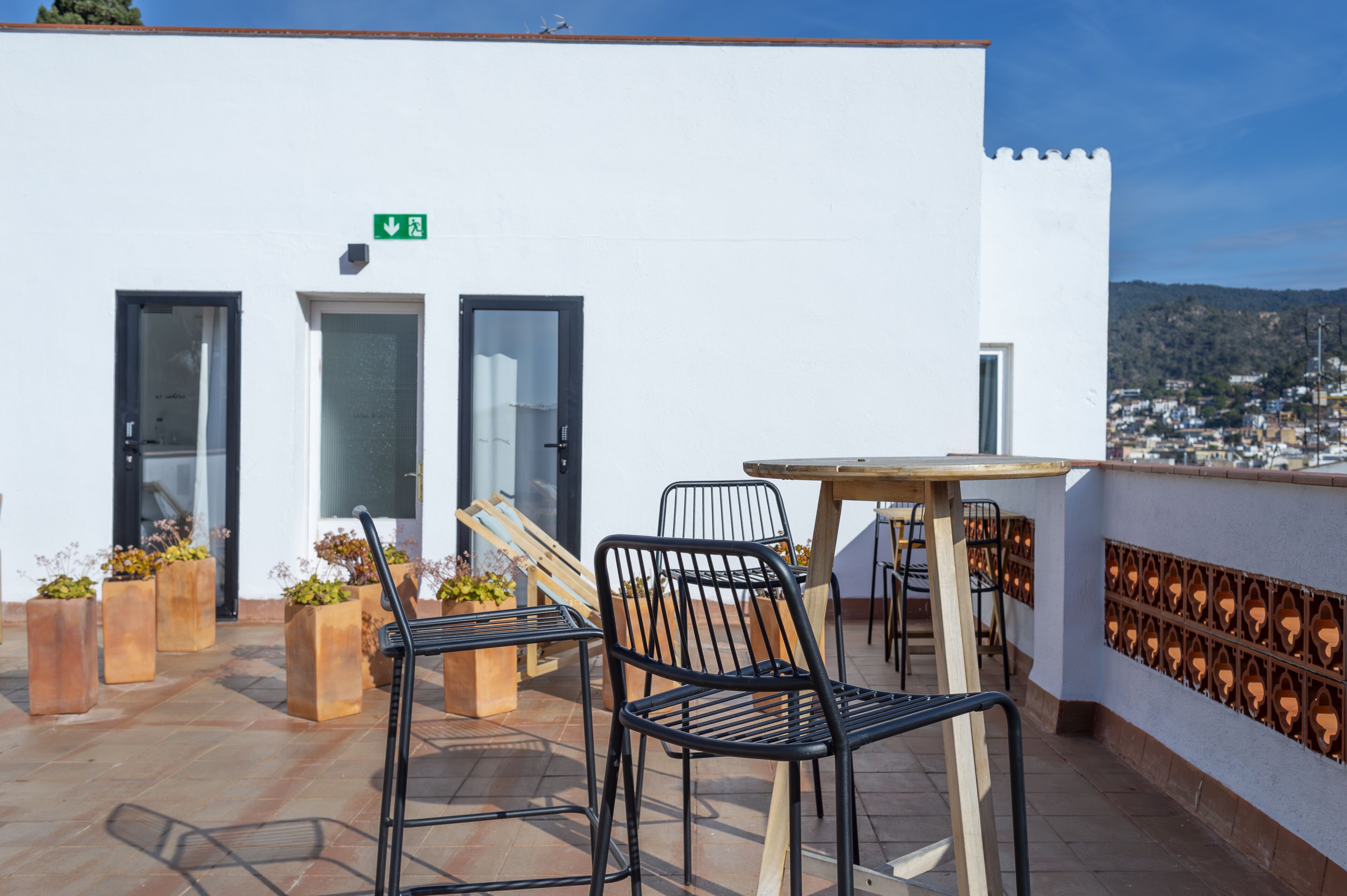 A terrace with outdoor seating, a table, and potted plants.