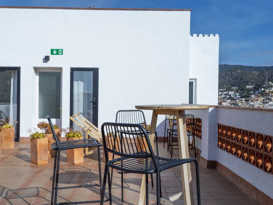Una terraza con mobiliario exterior, una mesa y plantas en macetas.