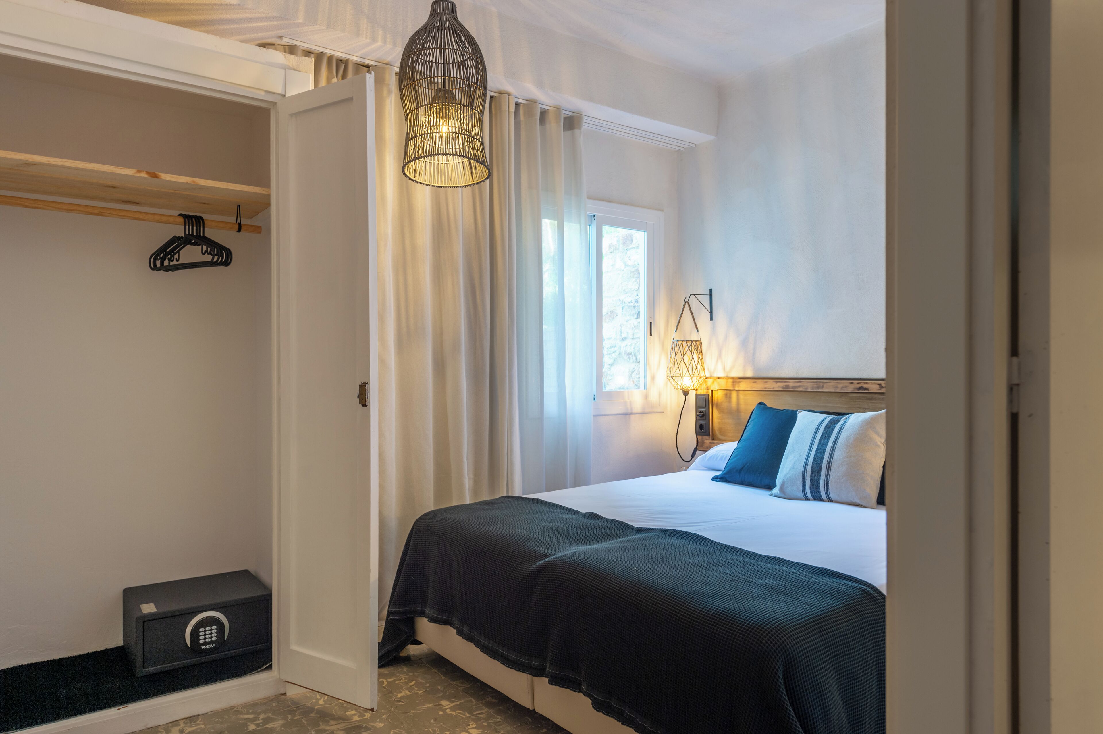 Une chambre d’hôtel équipée d’un lit, d’une lampe de chevet, d’un porte-manteau et d’un coffre-fort.