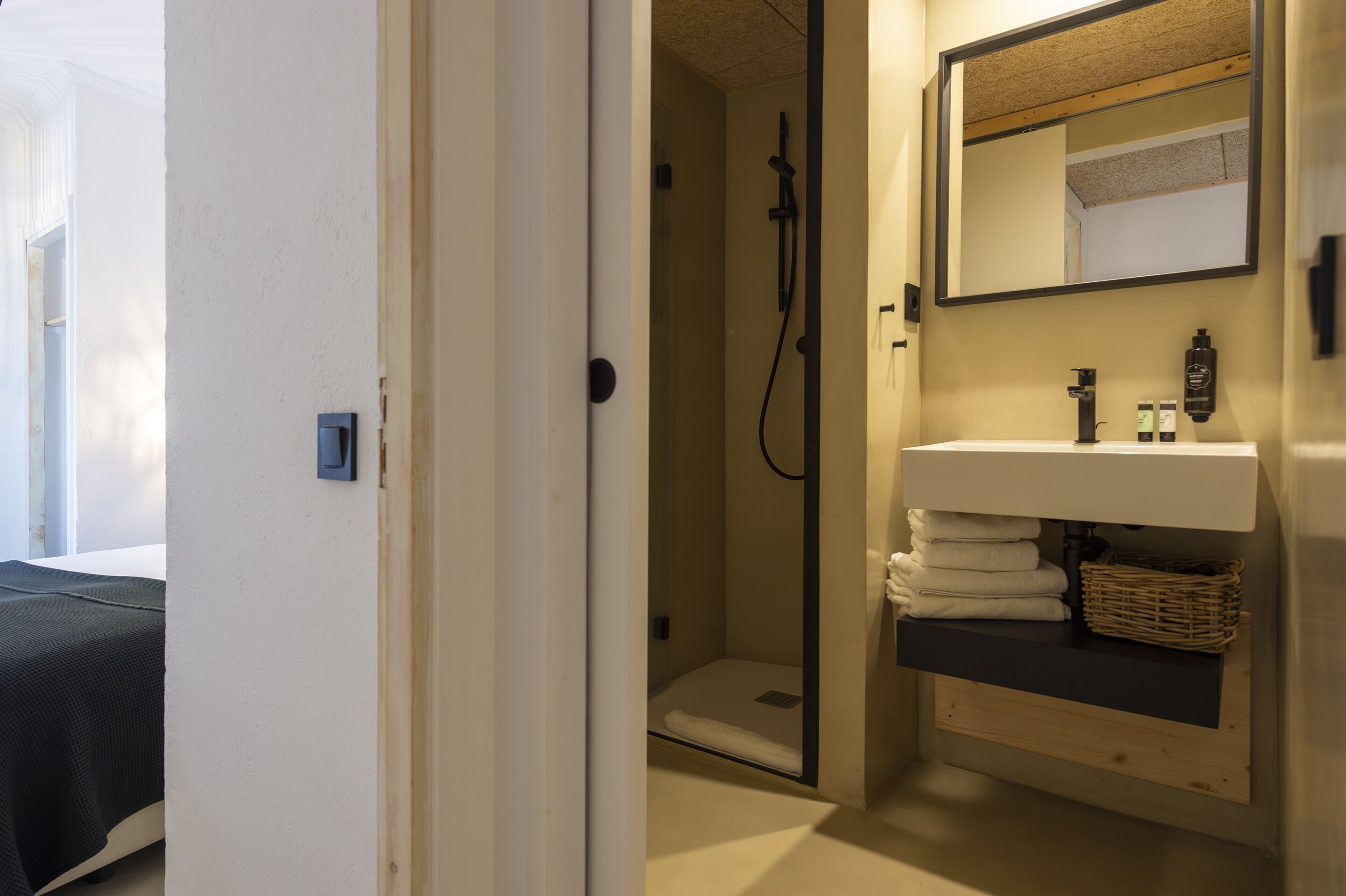 A bathroom with a shower, a sink with a mirror, and a towel rack.