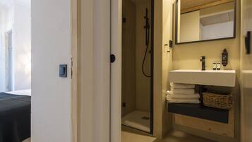 A bathroom with a shower, a sink with a mirror, and a towel rack.