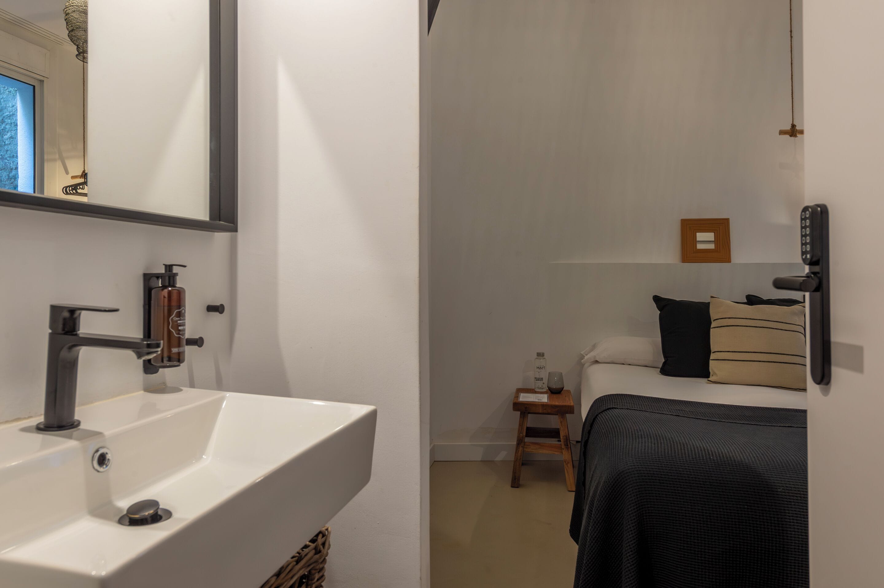 Un baño moderno con un lavamanos blanco, un espejo y una zona de ducha.
