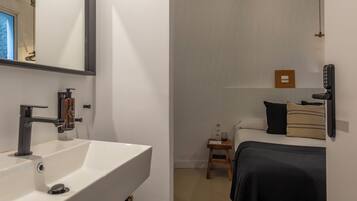 Un baño moderno con un lavamanos blanco, un espejo y una zona de ducha.