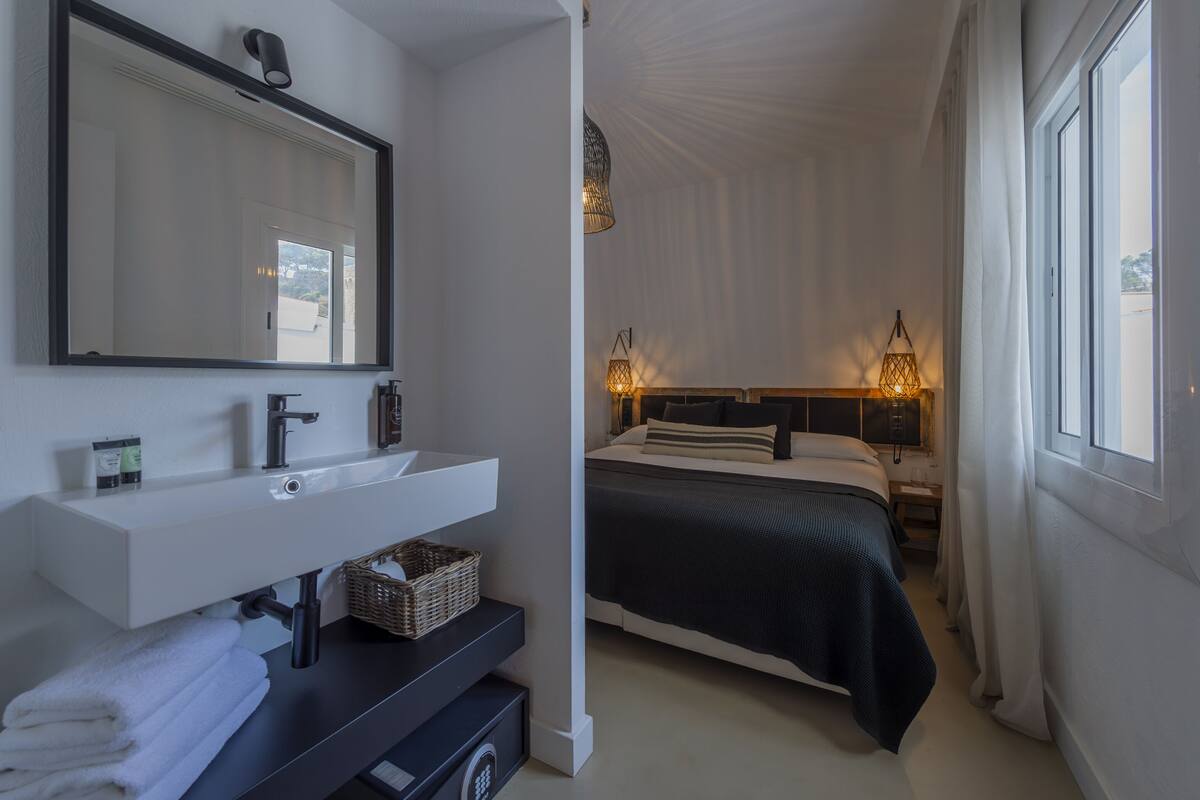 A bedroom with a bed, bedside lamps, a nightstand, and a large window.