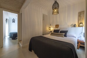Une chambre avec un grand lit, un luminaire suspendu et une table de chevet avec une lampe.