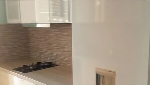A kitchen with a modern design, featuring a stainless steel countertop, a built-in stove, and white cabinetry.