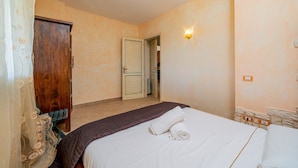 Un dormitorio con una cama, un armario de madera, una puerta y una lámpara fijada a la pared.